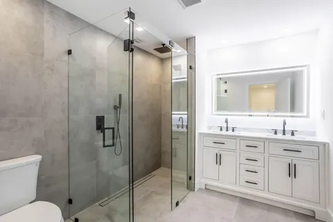 a bathroom with a double vanity sink toilet mirror and shower