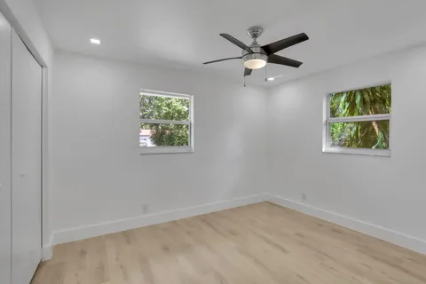an empty room with window and ceiling fan