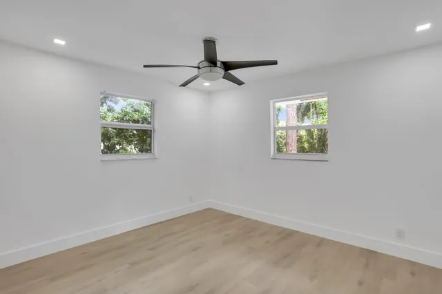 an empty room with a window and ceiling fan