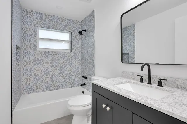 a bathroom with a granite countertop sink a toilet and bathtub