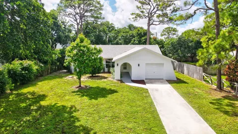 an aerial view of a house with a yard and trees all around
