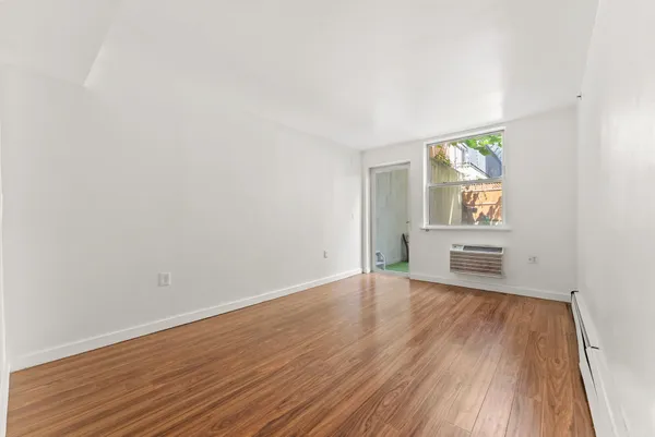 a view of an empty room and window with wooden floor