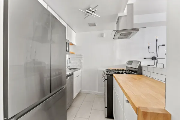 a kitchen with stainless steel appliances granite countertop a refrigerator a stove and a sink with wooden floor
