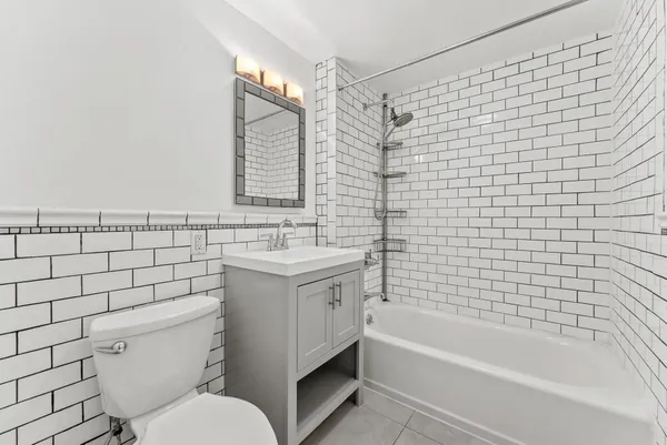 a bathroom with a bathtub shower sink mirror and toilet