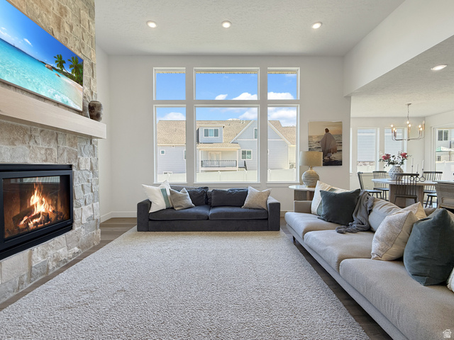 916 Rocky Mountain Way Elk Ridge, UT 84651 - Photo 9 of 54 Living area featuring wood finished floors, a fireplace, a textured ceiling, and hanging lights