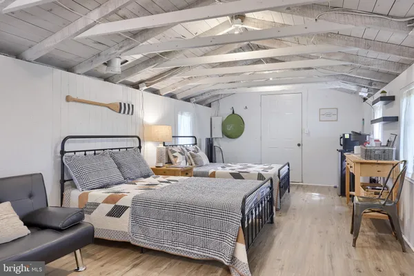 a bedroom with a bed a desk and chair with wooden floor