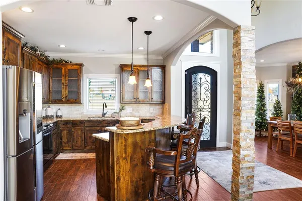 a kitchen with stainless steel appliances granite countertop a stove top oven a sink dishwasher a dining table and chairs with wooden floor