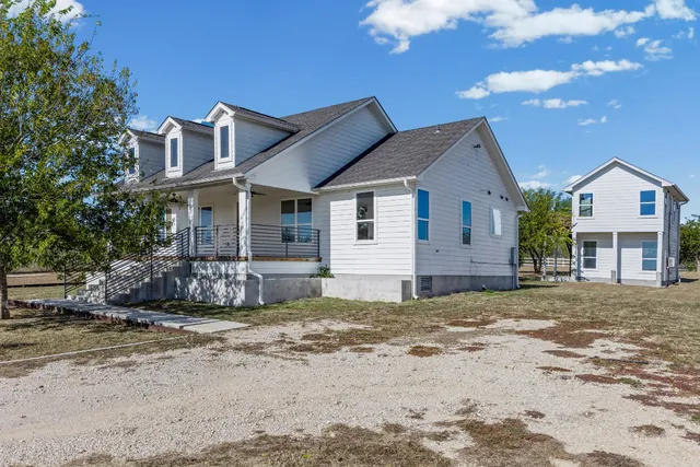 a view of a house with a big yard and large tree