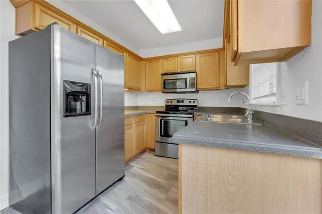 a kitchen with stainless steel appliances granite countertop a refrigerator a stove and a sink with wooden floor