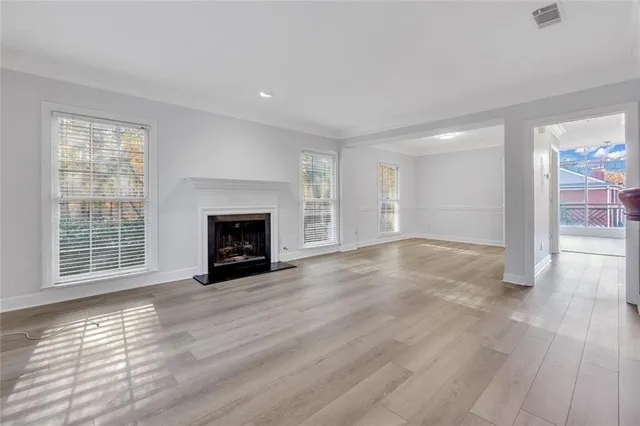 a view of an empty room with wooden floor fireplace and a window