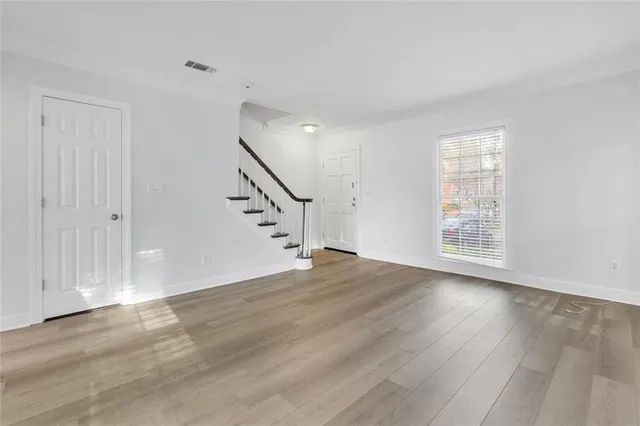a view of an empty room with wooden floor and stairs