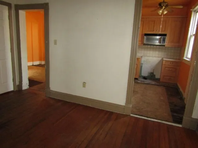 a view of a refrigerator in kitchen and an empty room