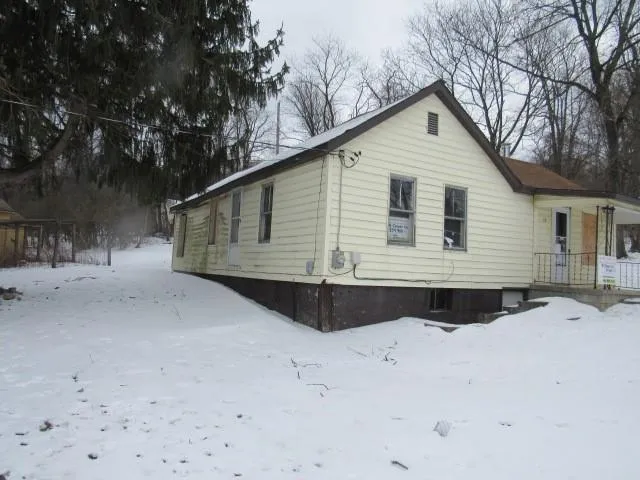 a view of house with yard and trees in the background