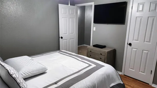 a bedroom with a bed and a flat tv screen on a dresser