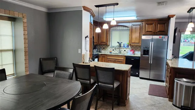 a room with stainless steel appliances kitchen island a table and chairs in it