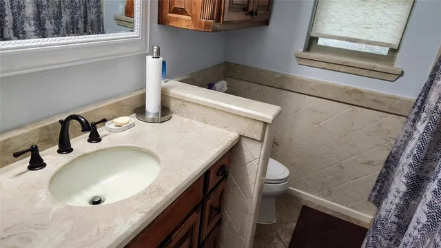 a bathroom with a granite countertop sink and a toilet