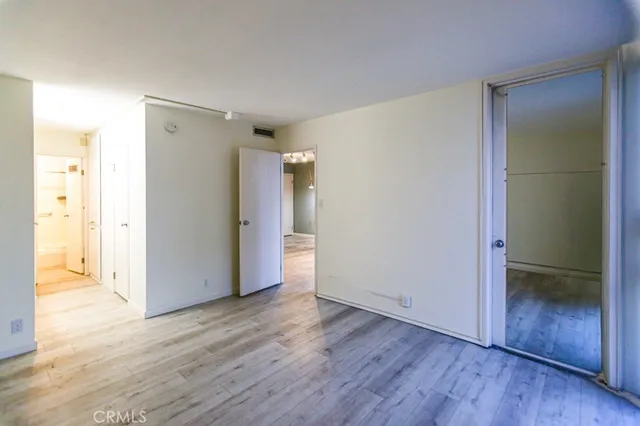 a view of an empty room with wooden floor and a bathroom