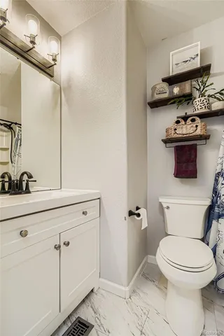 a bathroom with a toilet a sink and wooden floor