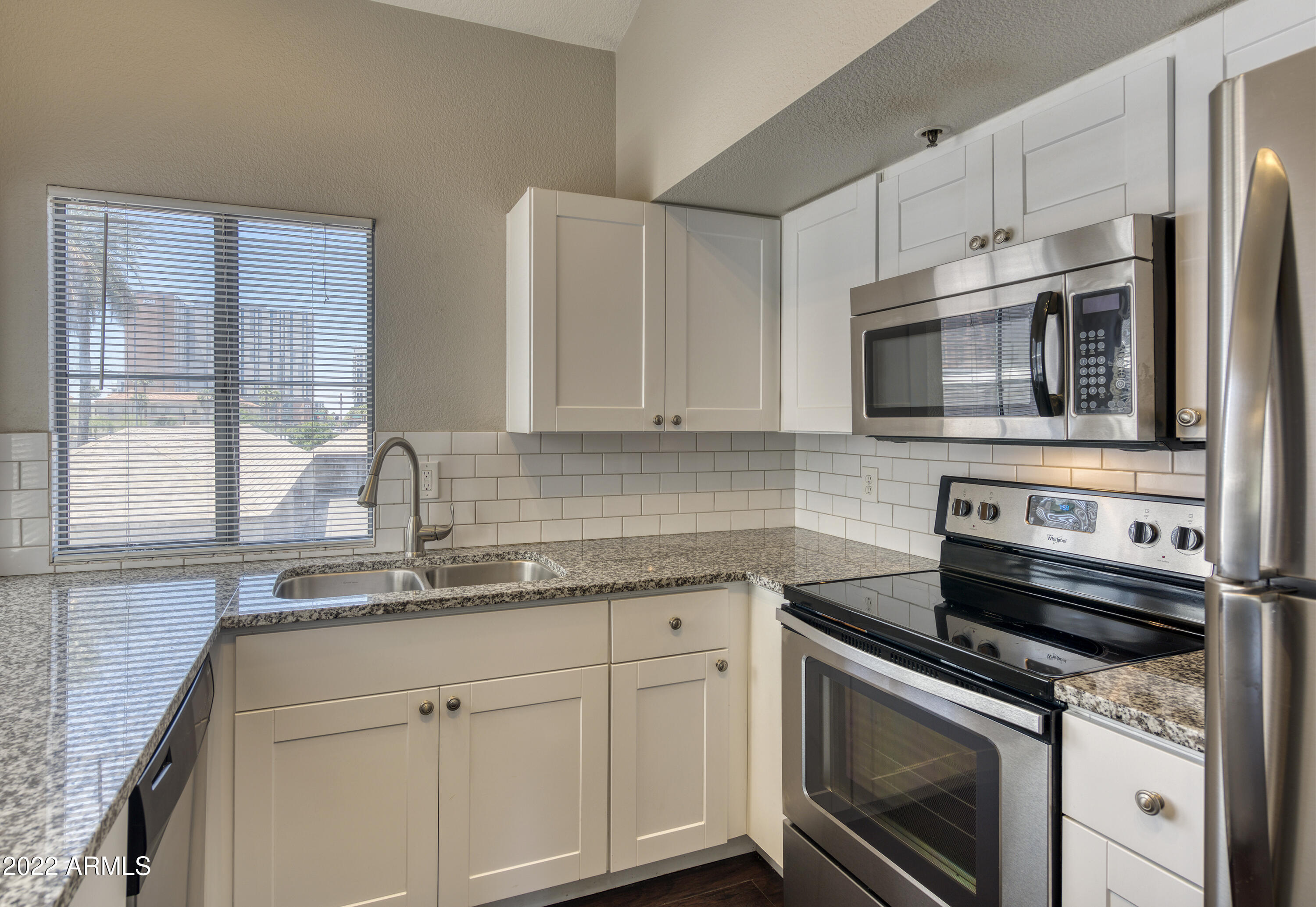 100 East Fillmore Street, Unit 201 Phoenix, AZ 85004 - Photo 13 of 23 a kitchen with granite countertop white cabinets stainless steel appliances and a sink