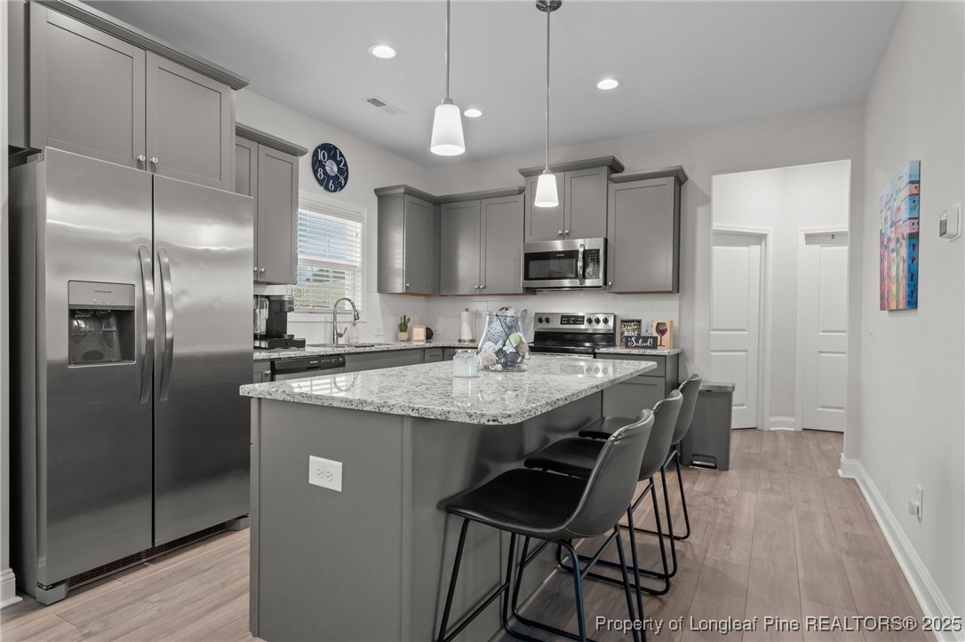 1660 Stackhouse Drive Fayetteville, NC 28314 - Photo 13 of 44 a kitchen with stainless steel appliances granite countertop a sink a stove a refrigerator and island with wooden floor