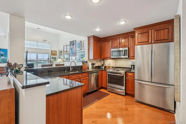 a kitchen with stainless steel appliances granite countertop a refrigerator a sink dishwasher a stove with wooden cabinets and floor