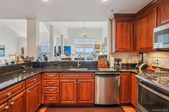 a kitchen with stainless steel appliances granite countertop a stove a sink dishwasher and cabinets with wooden floor