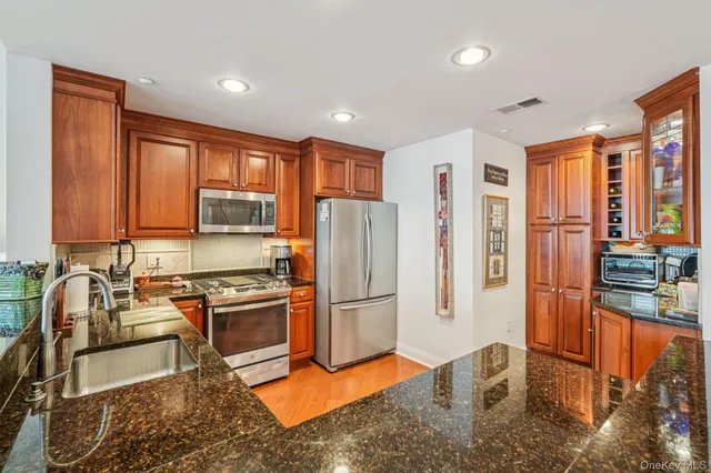 a kitchen with stainless steel appliances granite countertop a refrigerator stove top oven and sink