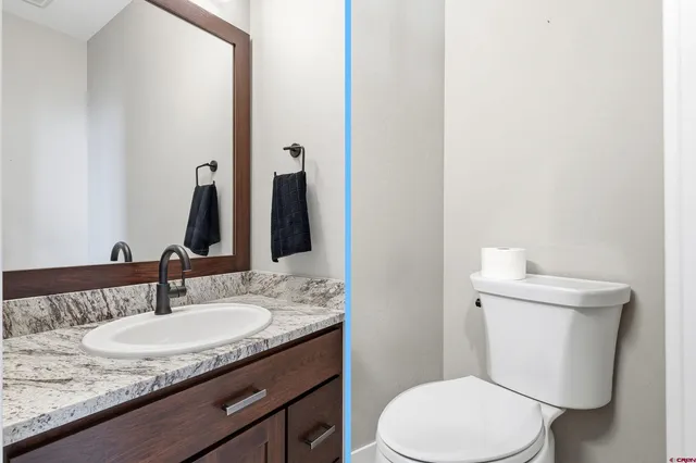 a bathroom with a granite countertop toilet sink and mirror