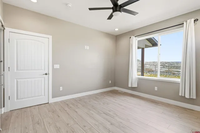 an empty room with wooden floor fan and windows