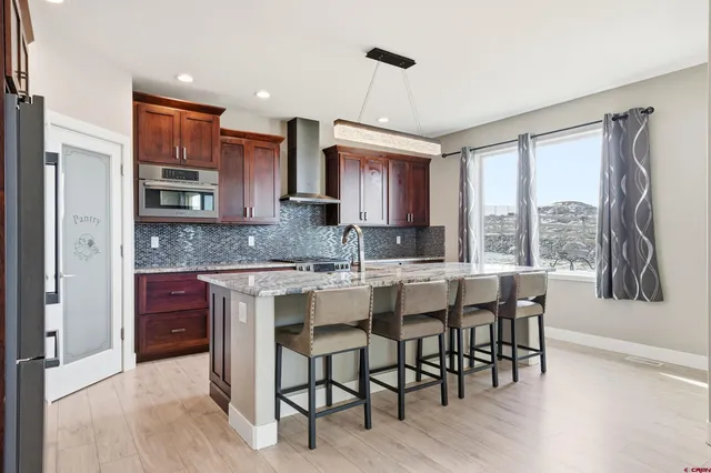 a kitchen with stainless steel appliances granite countertop wooden cabinets a refrigerator a sink a stove and a microwave