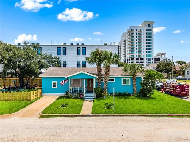 a front view of a residential apartment building with a yard and potted plants