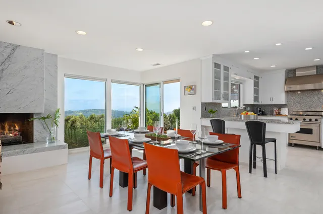 a open dining room with stainless steel appliances a dining table chairs and a floor to ceiling window