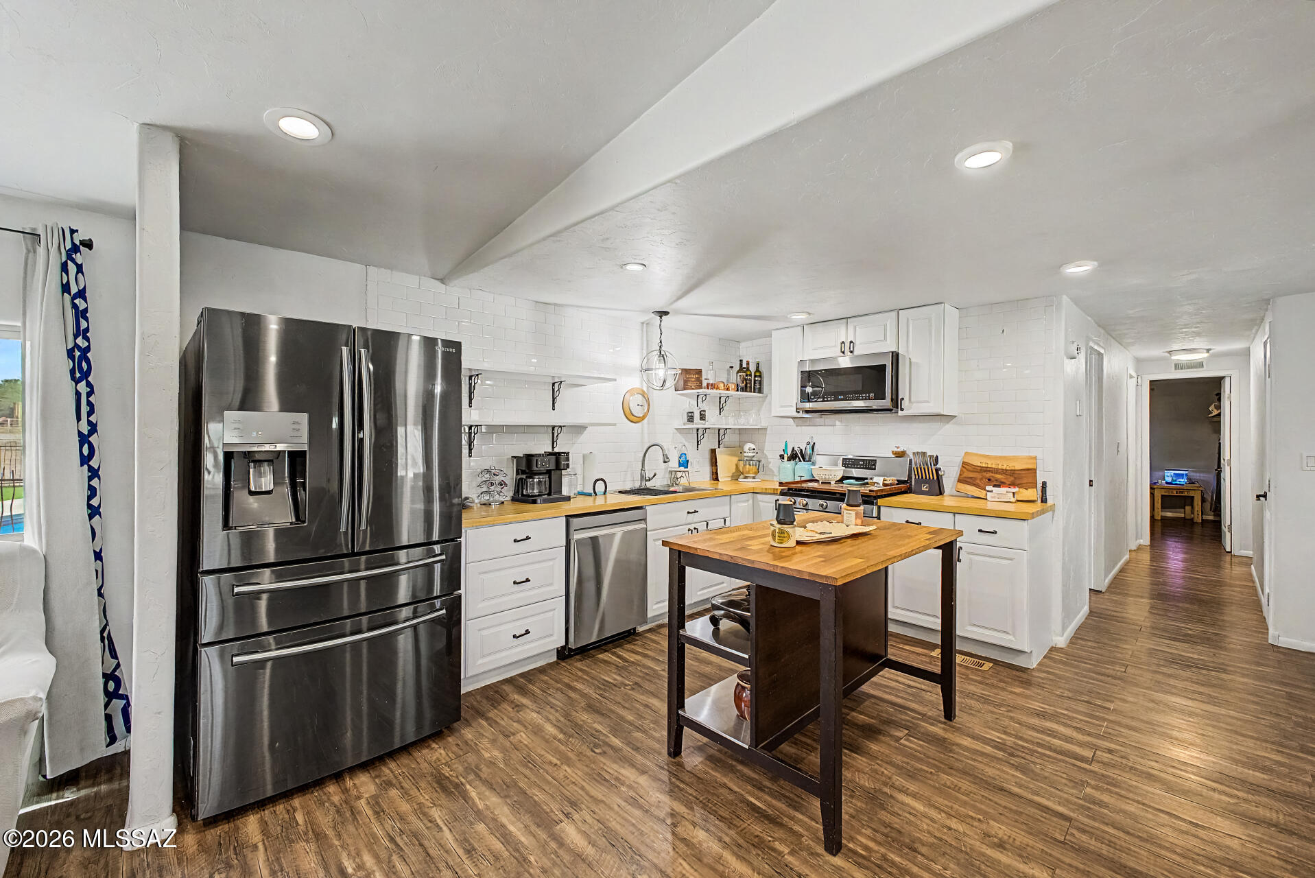 4231 East Pinal Street Tucson, AZ 85739 - Photo 10 of 36 a kitchen with stainless steel appliances a refrigerator a stove top oven a sink dishwasher and a dining table with wooden floor
