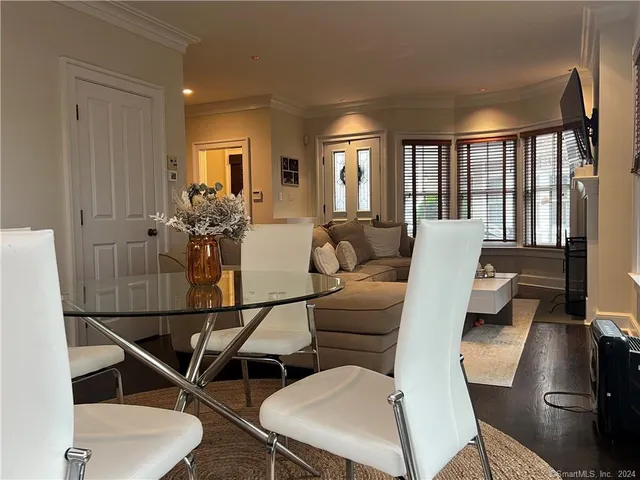a living room with furniture a flat screen tv and floor to ceiling window