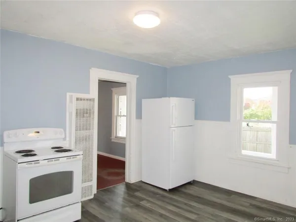 a view of a kitchen with a stove wooden cabinets and wooden floor