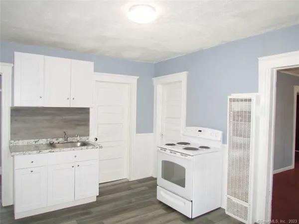 a kitchen with granite countertop white cabinets and white appliances