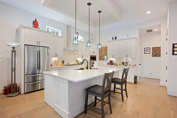 a kitchen with stainless steel appliances a refrigerator a sink dishwasher a dining table and chairs with wooden floor