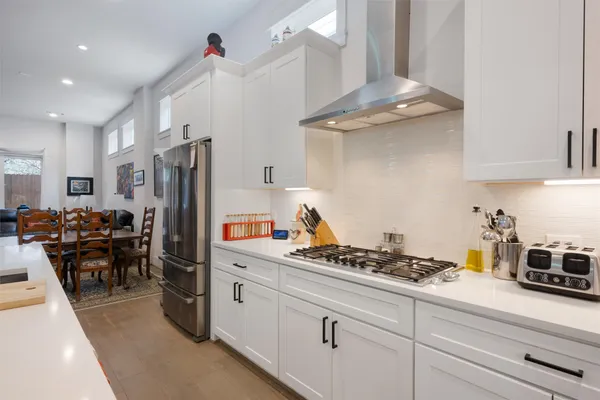 a kitchen with stainless steel appliances granite countertop a refrigerator a stove a sink dishwasher and a dining table with wooden floor