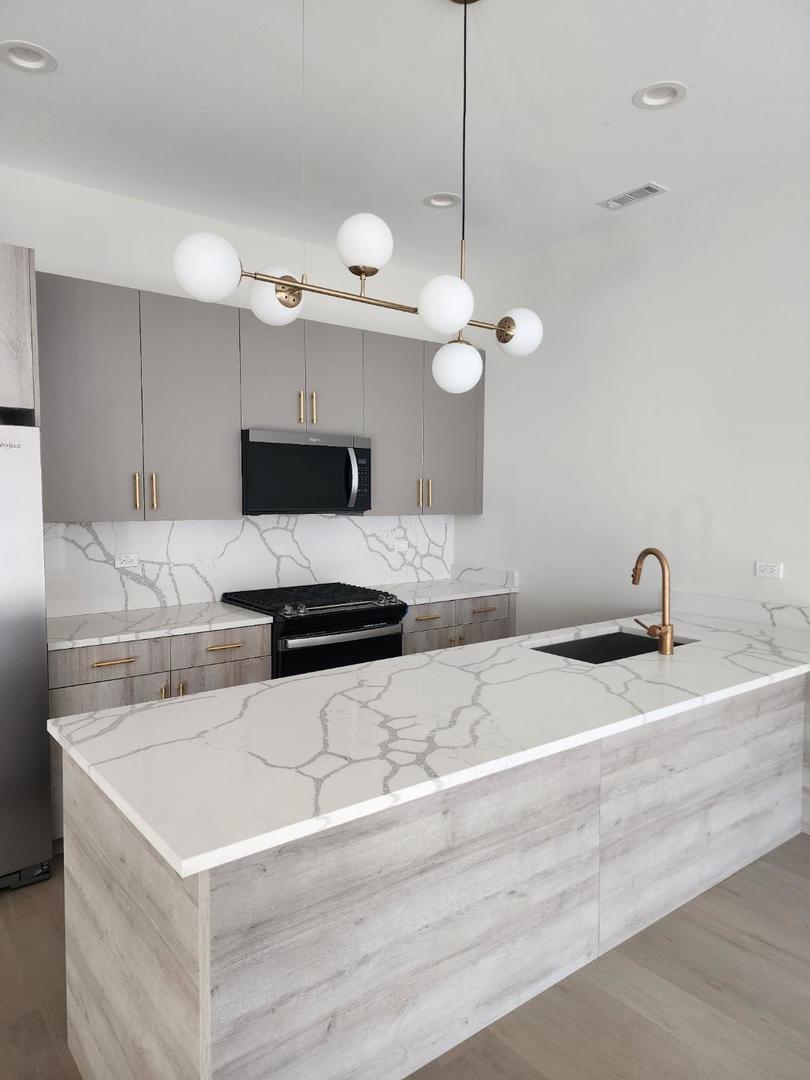 4625 South Michigan Avenue, Unit 2 Chicago, IL 60653 - Photo 4 of 21 a kitchen with granite countertop a sink a counter top space appliances and cabinets