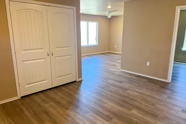 an empty room with wooden floor and closet area