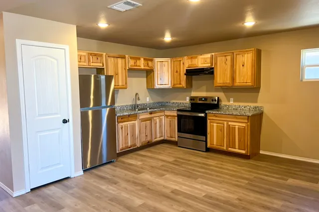 a kitchen with granite countertop a refrigerator and wooden cabinets