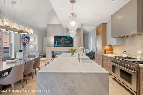a kitchen with stainless steel appliances a stove a sink a microwave a dining table and chairs