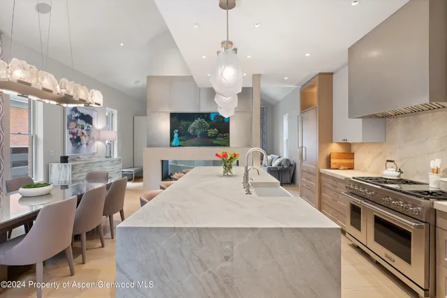 a kitchen with stainless steel appliances a stove a sink a microwave a dining table and chairs