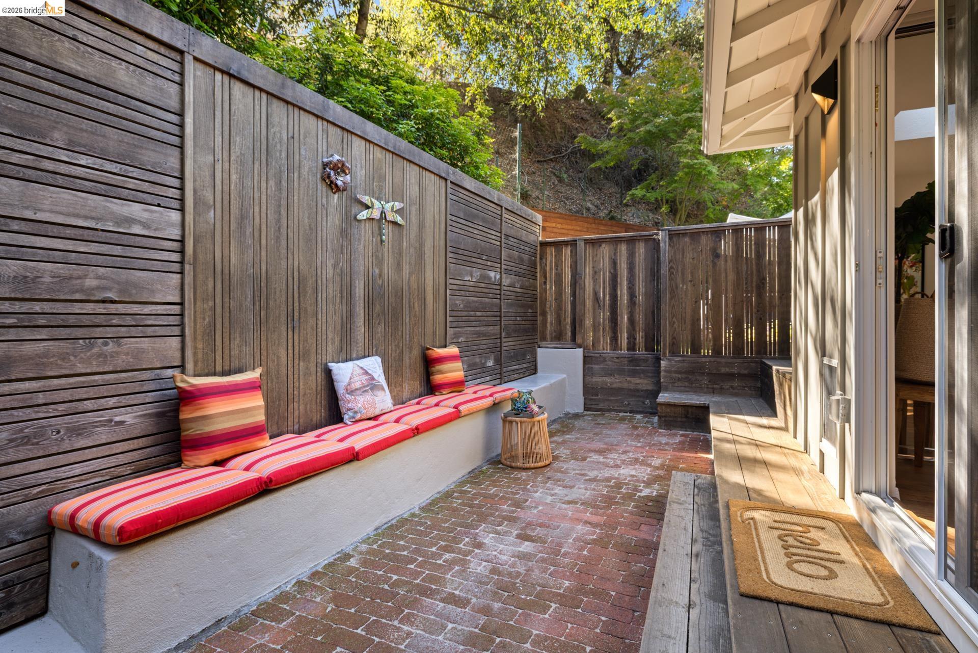 6660 Sobrante Road Oakland, CA 94611 - Photo 35 of 48 Outdoor patio featuring brick paving, wood fencing, and a built-in stucco bench