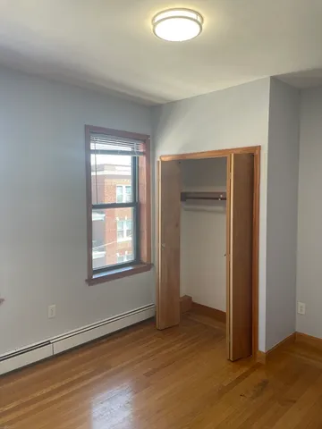 an empty room with wooden floor closet and windows