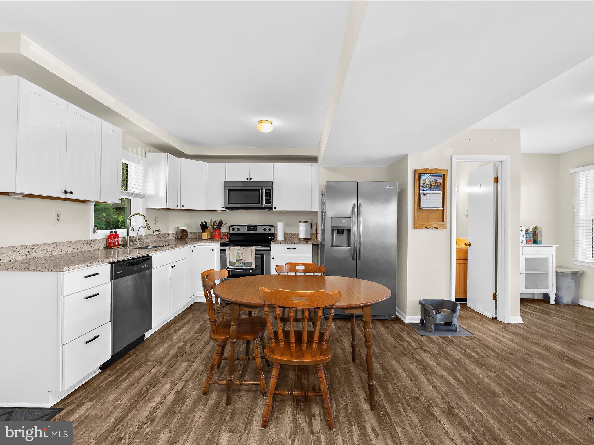 593 Riverside Drive Pasadena, MD 21122 - Photo 7 of 56 a kitchen with stainless steel appliances granite countertop a stove top oven a sink dishwasher a refrigerator and white cabinets with wooden floor