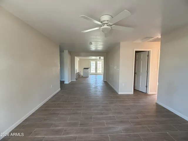 an empty room with wooden floor fan and windows
