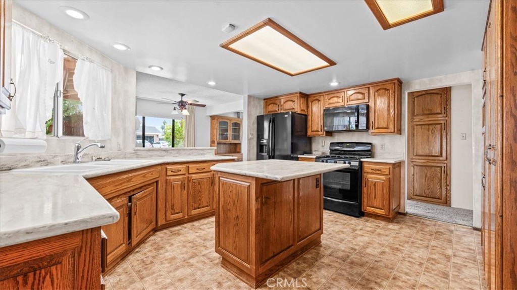 27196 10th Street Highland, CA 92346 - Photo 12 of 42 a kitchen with stainless steel appliances granite countertop a stove top oven a sink dishwasher and a refrigerator with wooden cabinets
