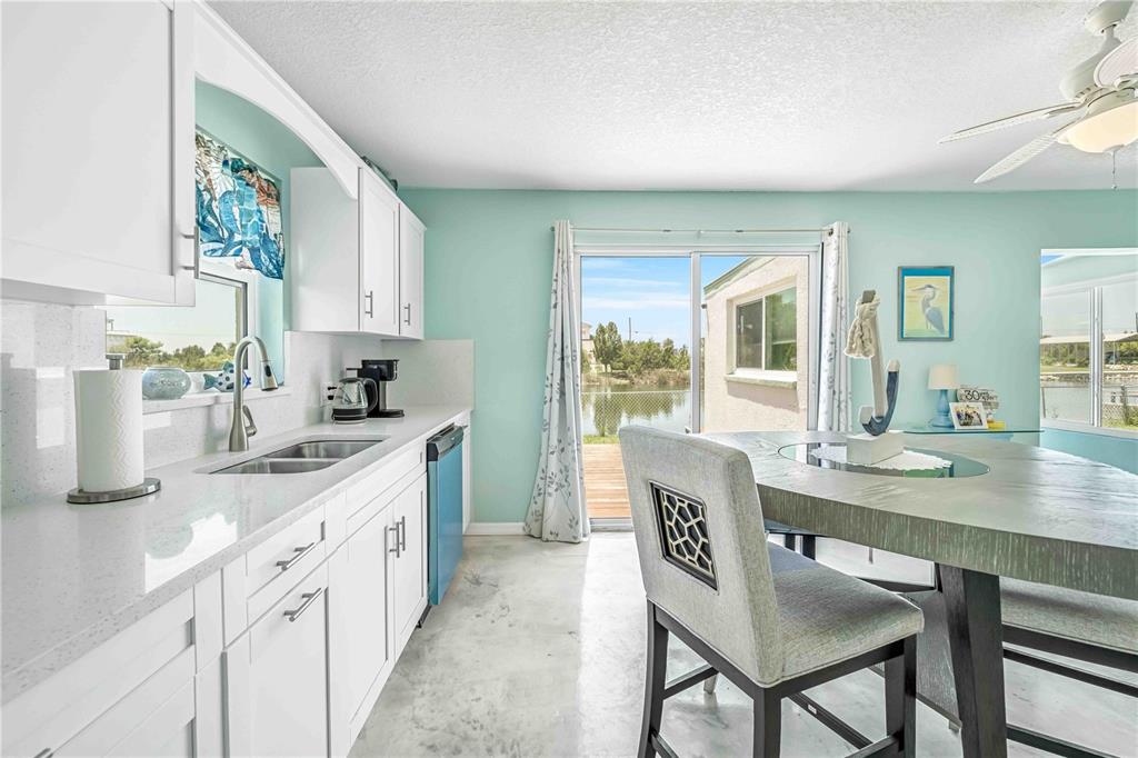 3379 Crape Myrtle Drive Hernando Beach, FL 34607 - Photo 13 of 68 a kitchen with granite countertop white cabinets and chairs