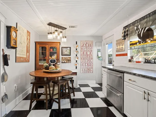 a kitchen with stainless steel appliances granite countertop a sink a stove a dining table and chairs